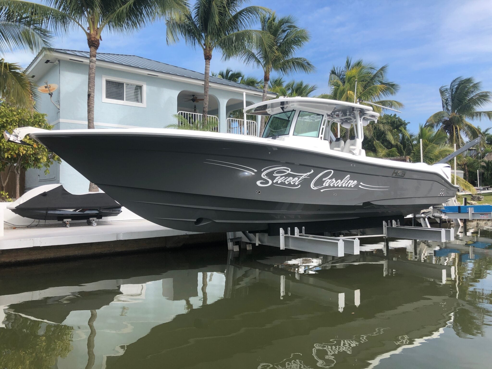 Center console boat raised on a boat lift at a waterfront home