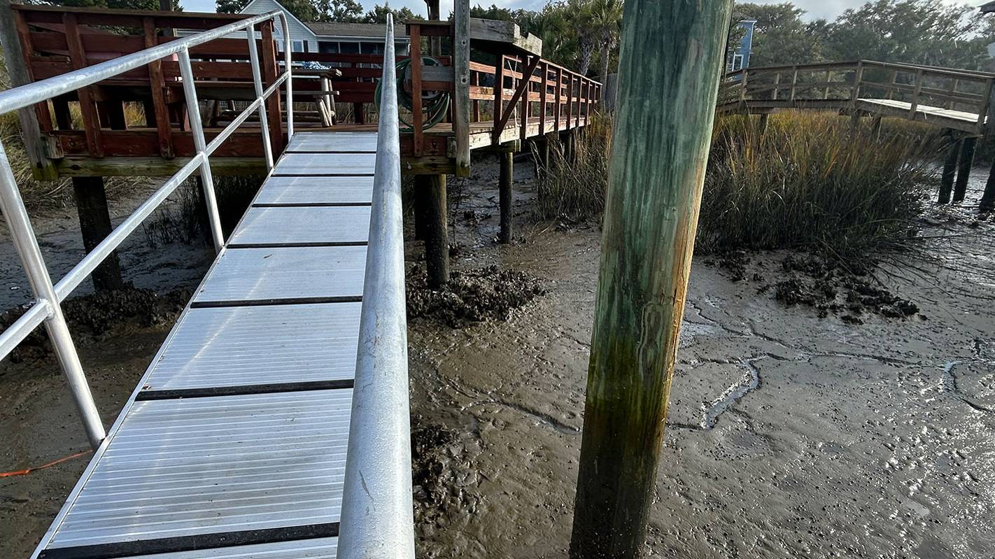 Aluminum gangway leading down to a dock over tidal mudflats near Charleston